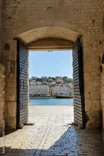 View through the historic entrance gate of Trogir towards the port in Dalmatia in late summer