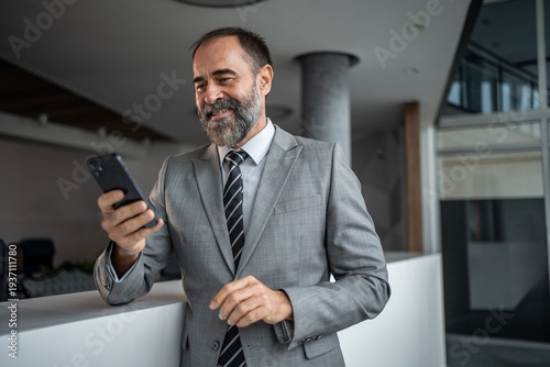 Photos Mature businessman checking smartphone, connecting with corporate technology
