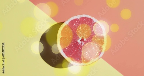 Displaying halved grapefruit with pink segments on two-tone backdrop, casting shadow and bokeh