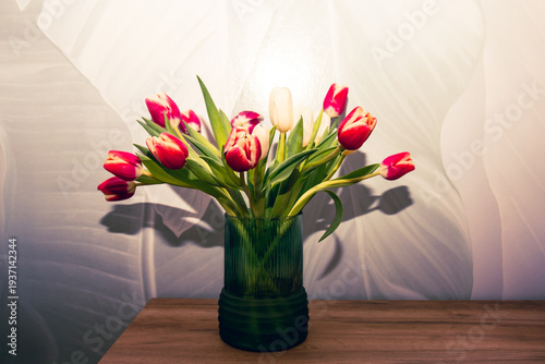 Bouquet of beautiful tulips in vase on wooden table against light green background