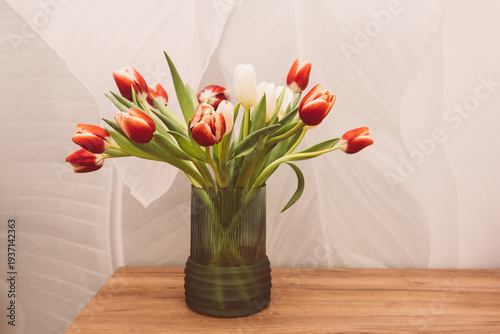 Bouquet of beautiful tulips in vase on wooden table against light green background