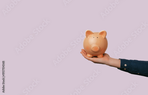 Hand Holding Ceramic Piggy Bank On Pastel Pink Background. Minimal Studio Composition Evoking Financial