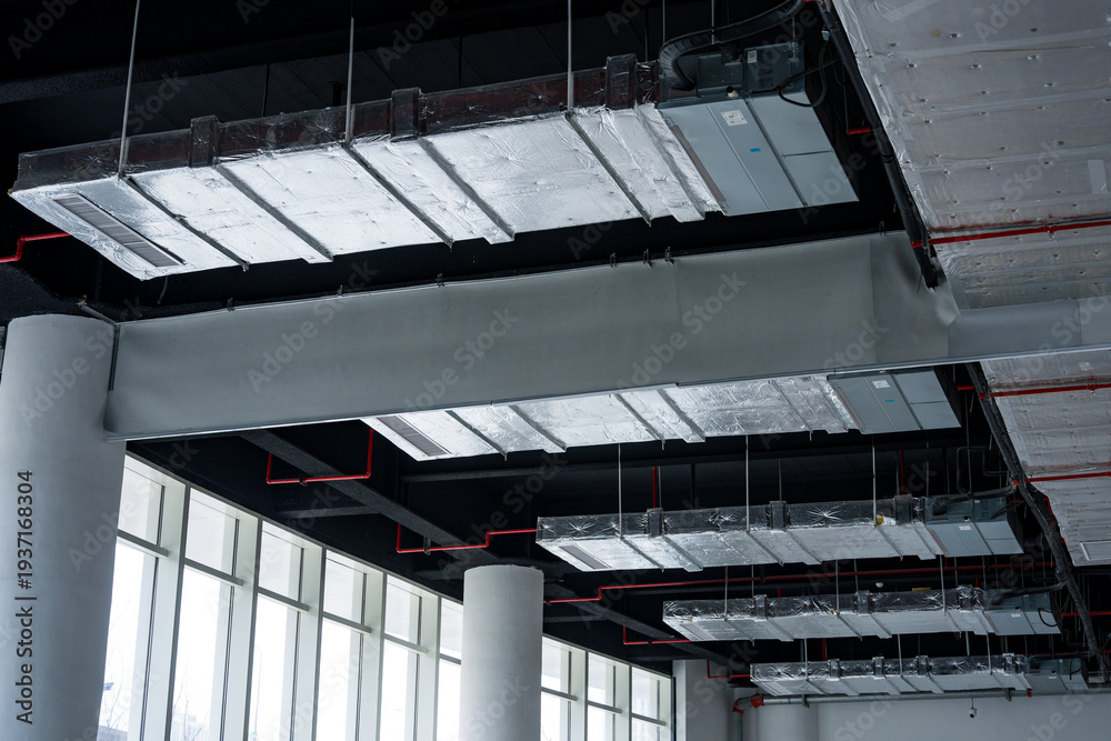 Fototapeta premium Modern interior space with exposed ceiling structure featuring steel beams and ductwork