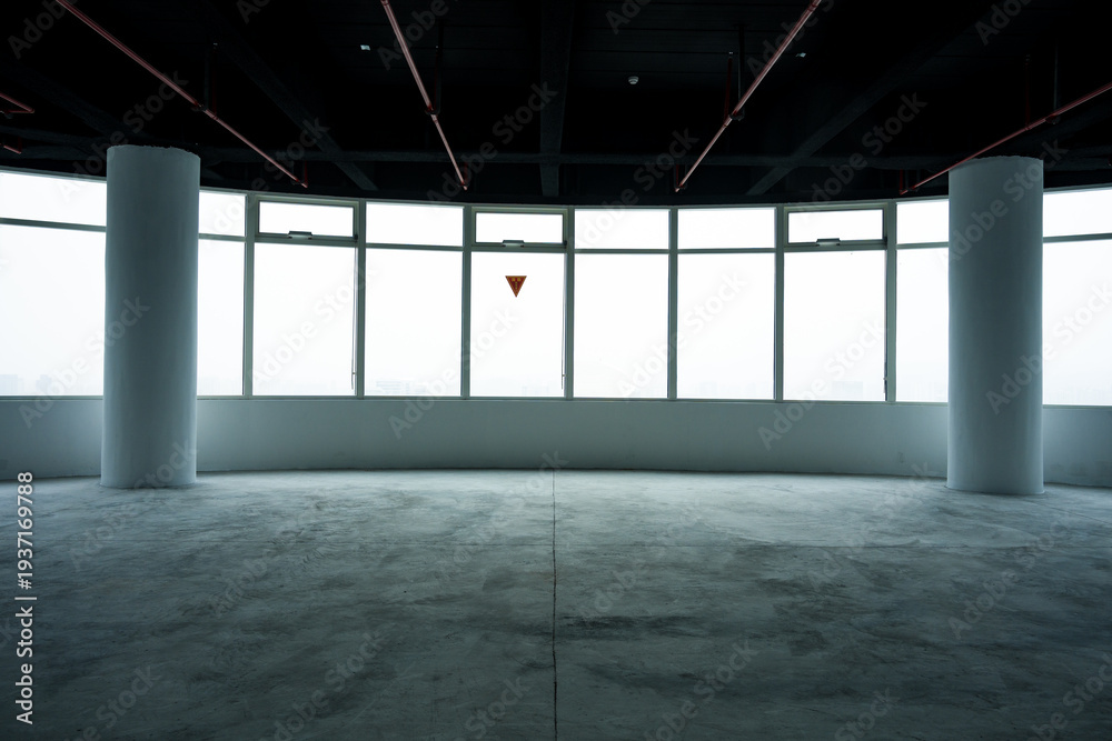 Fototapeta premium Spacious empty office with floor-to-ceiling windows and concrete flooring