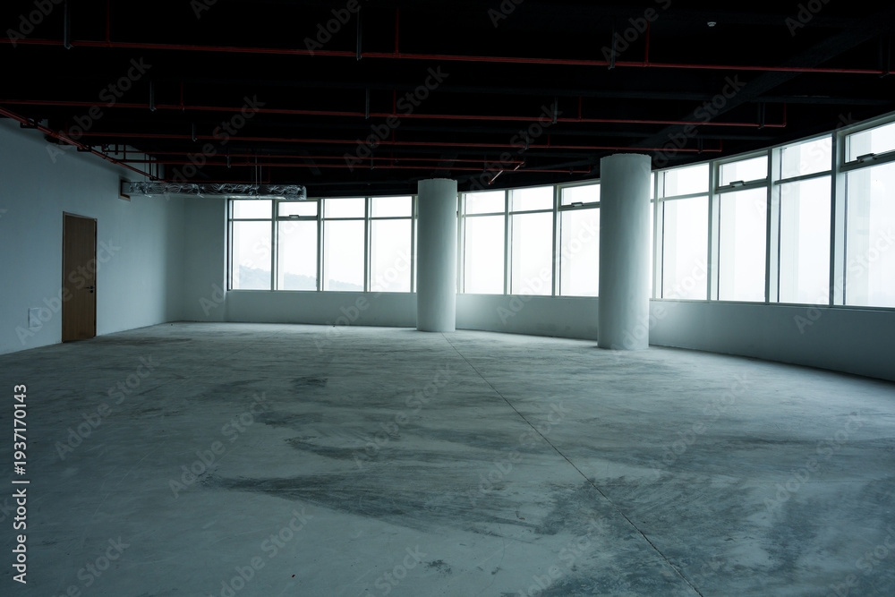 Fototapeta premium Empty unfinished office interior space with concrete floor columns and large windows