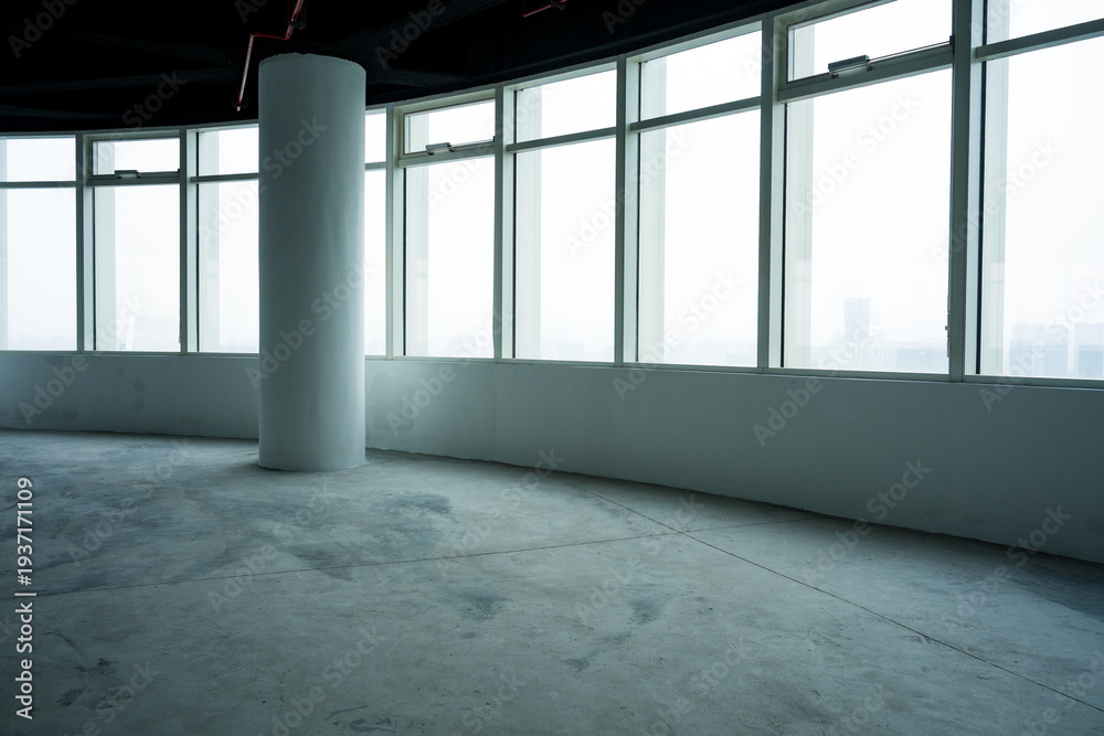 Fototapeta premium Empty office interior with floor-to-ceiling windows, white column, and concrete floor