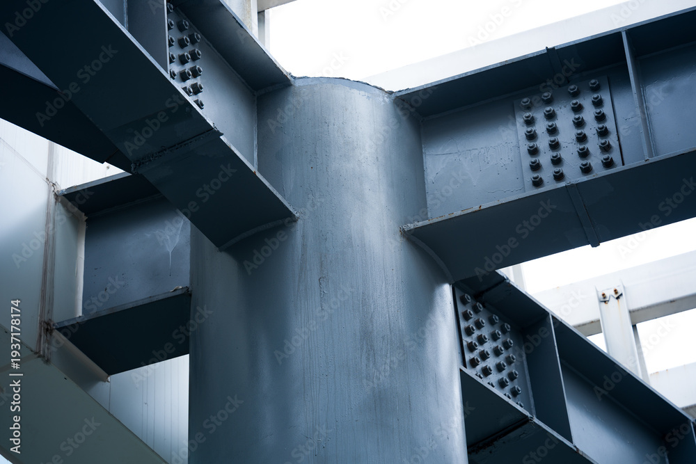 Fototapeta premium Close-up of steel structural column intersecting with riveted cross beams at joint node