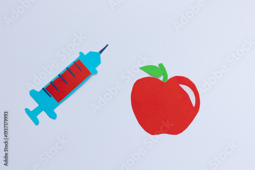 Apple next to a syringe on a white background. Concept about chemicals in fruit, pesticides, genetically modified foods, and the debate over food safety and health, represented with paper cut figures