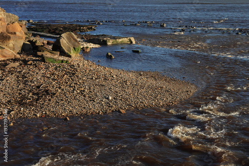 Rocky beach with a stream flowing into the sea 