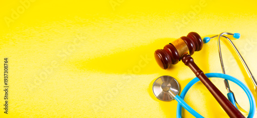 stethoscope and rubber gavel on yellow background