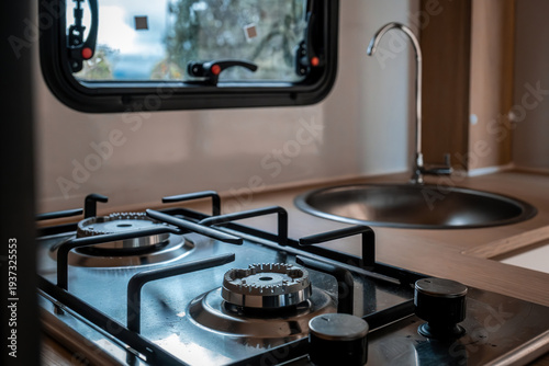 Modern camper van kitchen featuring a compact gas stove and round stainless steel sink, ideal for travel and van life