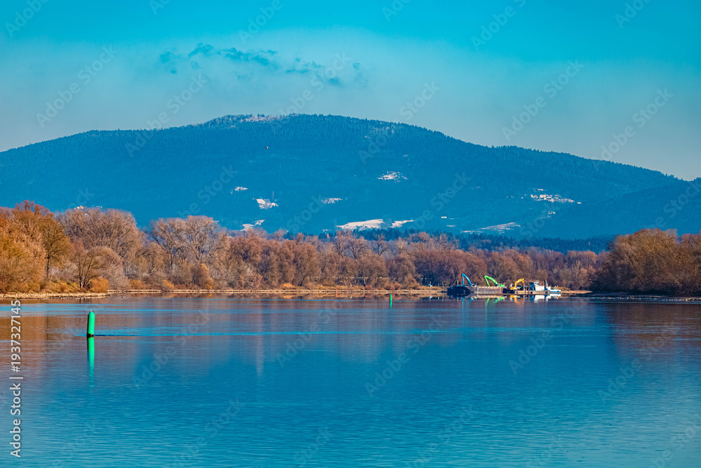 Fototapeta premium Winter landscape with reflections in river Danube and the Bavarian forest in the background on a sunny winter day at Stephansposching, Danube, Deggendorf, Bavaria, Germany