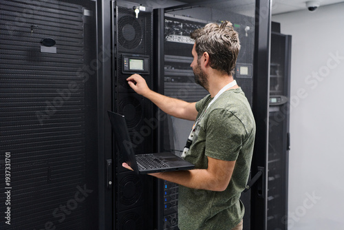 Foto IT technician configuring server equipment in a data center while holding a lapt