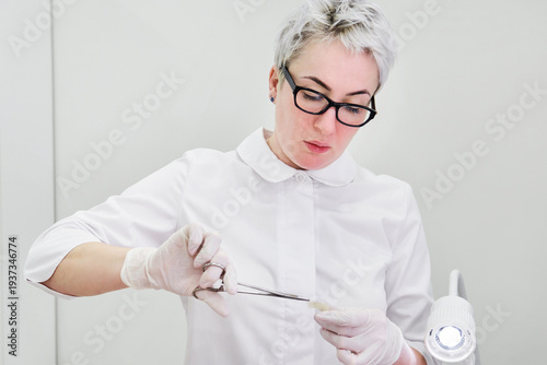 Canvas-taulu Doctor wearing gloves using a surgical forceps to open band aid