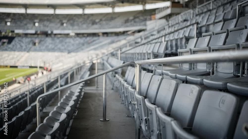 Empty upper deck grandstand seating in medium shot crisp focus on metallic railings and geometric seat patterns soft focus on distant game area below.