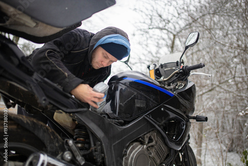 A man maintains a motorcycle in winter, motorcycle repair and maintenance