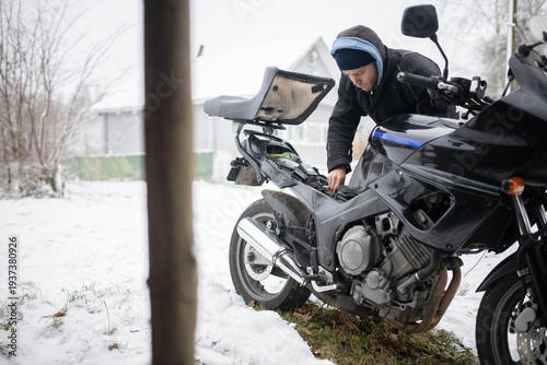 A man maintains a motorcycle in winter, motorcycle repair and maintenance