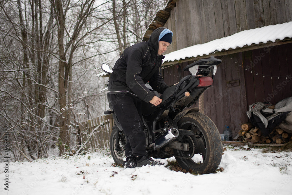 Fototapeta premium A man maintains a motorcycle in winter, motorcycle repair and maintenance