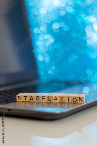 Stagflation financial business concept with wooden blocks on laptop silver blue bokeh copy space