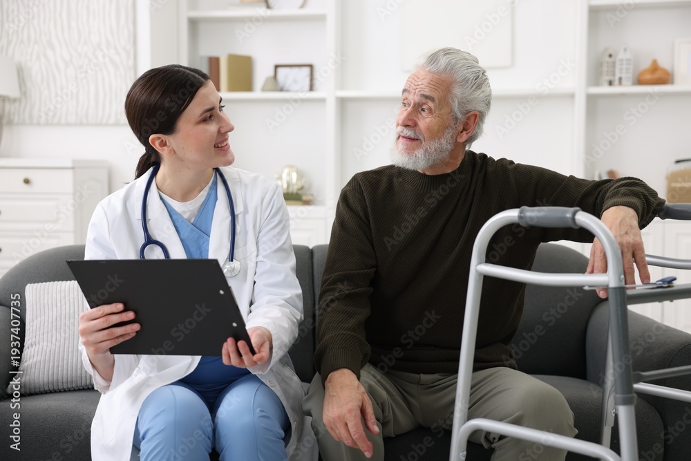 Obraz premium Care worker with clipboard talking to senior man indoors