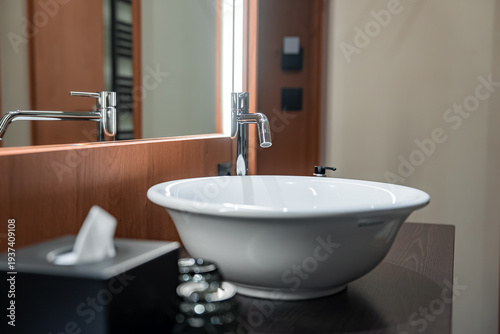 Φωτογραφία White vessel sink and tall chrome faucet on dark wood countertop, warm wood mirr