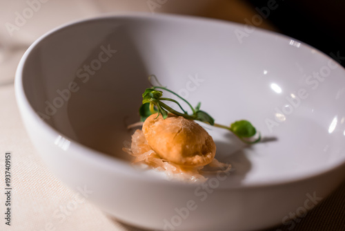 A golden fried dumpling rests on pickled vegetables and microgreens in a deep white bowl, warm focused lighting and shallow depth of field suggest fine dining in the Dolomites.