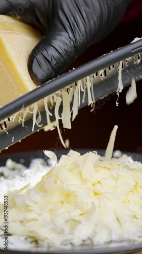 Culinary expert skillfully assembles cheese mound. Experienced cook meticulously stacks shredded parmesan to create elegant culinary display