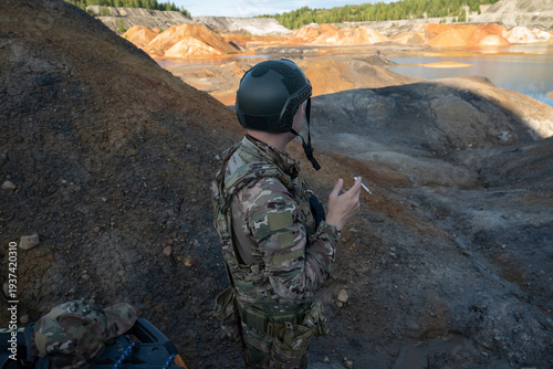 Armed Soldier in Military Uniform Smoking While Observing Quarry Landscape
