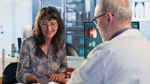Bild auf Leinwand Senior woman evaluating diagnostic results with her medic in a cabinet, using advanced tech tools to give the correct results to his patient