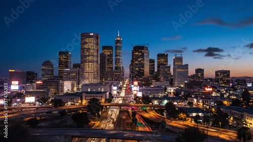 Cityscape at dusk with tall buildings and highway traffic, lit by golden hour light