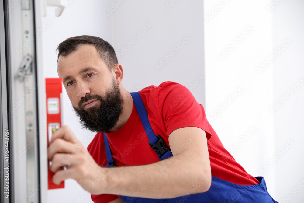 Fototapeta premium Worker measuring door with building level indoors
