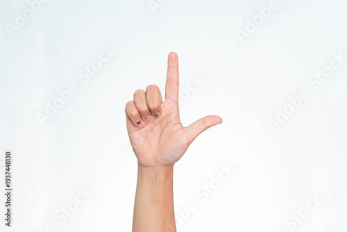 Close up of a human hand showing an L shaped finger gesture, commonly representing the letter L or a loser sign, on a white background.
