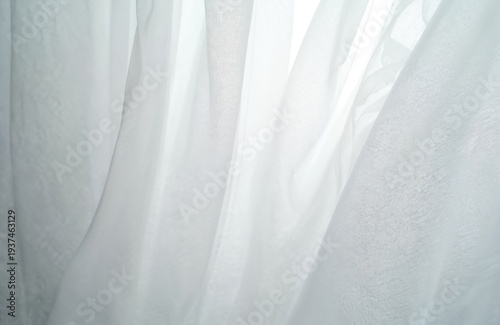 Sheer white fabric cascades softly creating abstract wavy folds. Light passes through thin material, offering subtle texture and delicate airy shapes. Minimalist background element.