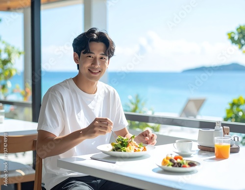 Happy young man enjoying a healthy breakfast at a seaside restaurant.