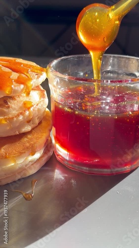 A close-up shot of golden honey being poured into a clear glass. The rich, flowing honey creates a visually appealing and appetizing food scene, perfect for culinary content.
