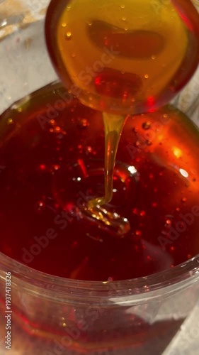 Close-up video of honey being poured into a jar. Ideal for food content, cooking, honey products, and natural ingredients.