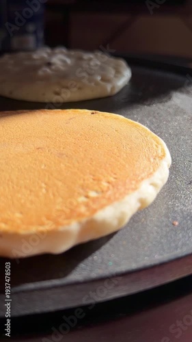 Close-up video of pancake batter cooking in a hot pan with bubbles forming. Perfect for food preparation, breakfast cooking, and culinary content.