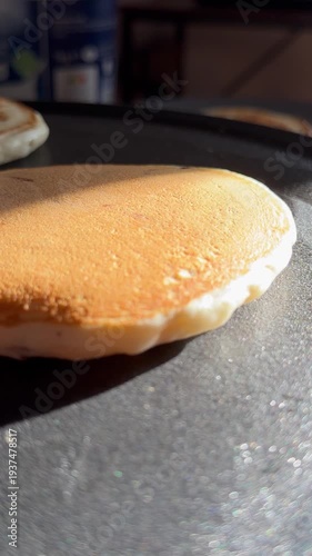 Close-up video of a golden pancake cooking in a hot pan, showcasing the delicious texture and cooking process. Ideal for food preparation and breakfast-related content.