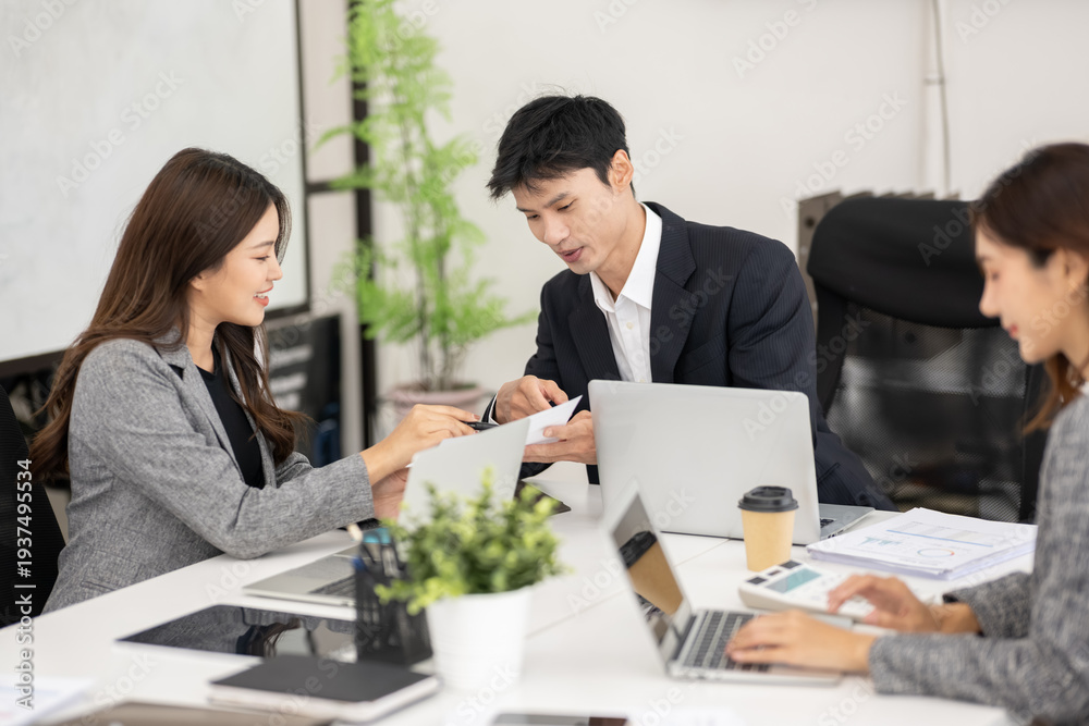Fototapeta premium Asian business team discussing documents during a meeting in modern office.