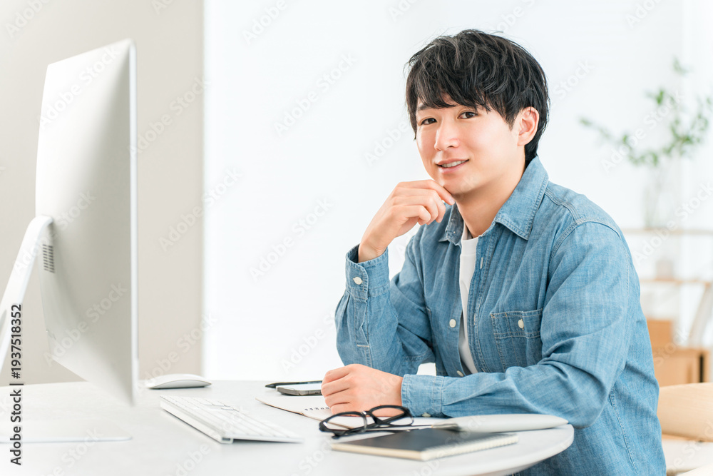 Naklejka premium A man using a computer at home to telework, online seminar, side job, video editing