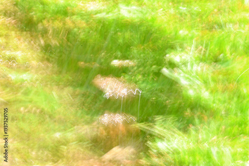 Dreamy abstract motion blur of green grass meadow with glowing light trails and ethereal white streaks