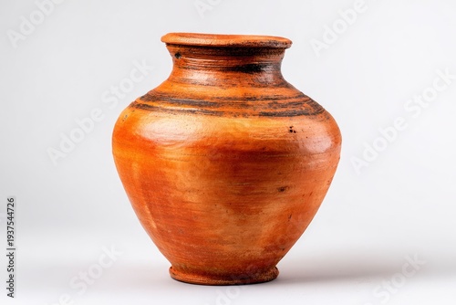 A rustic earthy reddish-brown ceramic pot with a rounded body and a narrow neck featuring dark horizontal bands stands on a light background