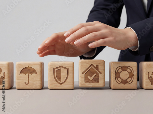 A person's hands hovering over wooden blocks representing various insurance types like umbrella, shield, home, and lifebuoy, symbolizing comprehensive protection, security, and risk manageme