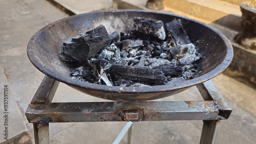 Charcoal in Metal Brazier for Barbecue Cooking and Traditional Fire Fuel. Black charcoal in a metal brazier on a steel stand for cooking