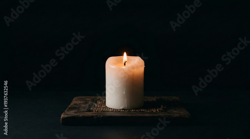 Soft white candle burning brightly on wooden board