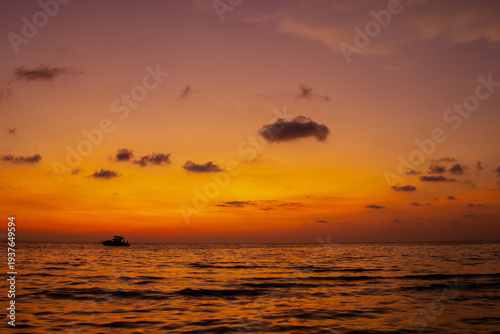 Warm tropical sunset over ocean water with orange gradient sky and soft clouds. Peaceful seascape background, travel destination mood and relaxing evening atmosphere. Thailand island view.