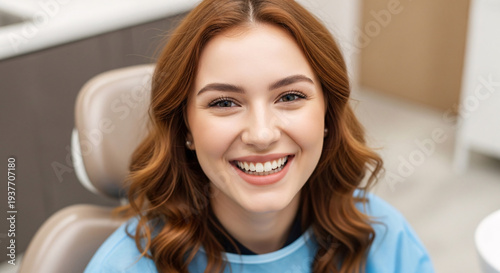 Happy young woman smiling in dental clinic sitting in dental chair with bright cheerful expression and healthy skin perfect for dental health promotion and patient care