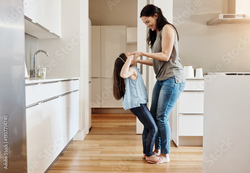 Foto Mom, girl and happy with dancing in kitchen for bonding, love or holding hands for balance in house