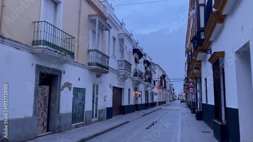 Empty street with typical Andalusian buildings featuring balconies and bay windows under a twilight sky
