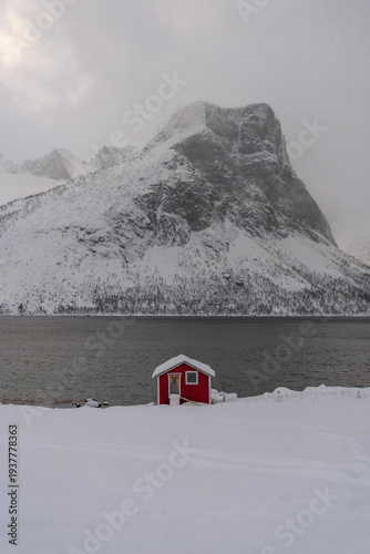 Casa de pescadores roja en Noruega, con fiordo y montaña detrás